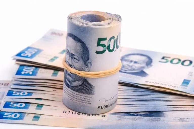 Rollo de billetes de 500 pesos mexicanos sobre una pila de efectivo, en estilo editorial moderno y aspiracional