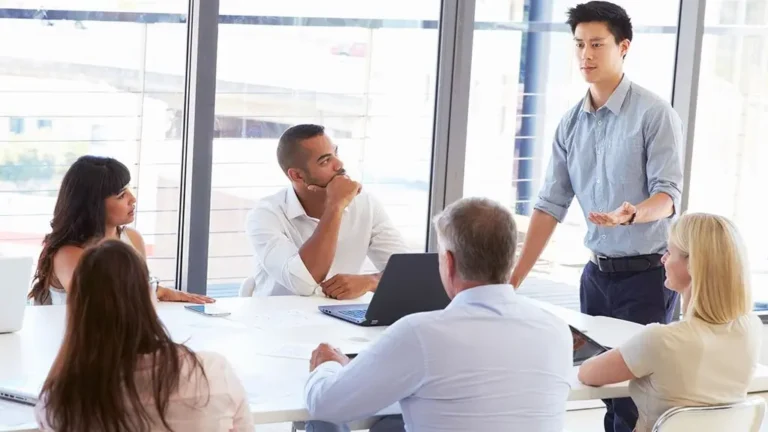 Gerente explicando responsabilidades a su equipo en oficina moderna representando el desafío de asignar tareas difíciles.