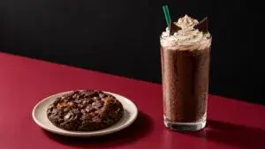 Black Cat Frappuccino acompañado por una galleta y artículos coleccionables de la campaña de Halloween de Starbucks.